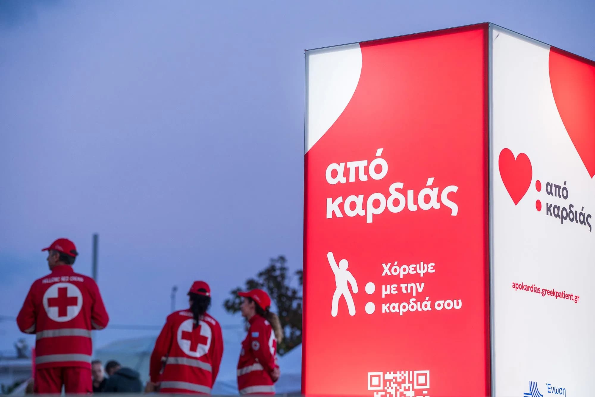 Φωτισμένο περίπτερο της εκστρατείας με εθελοντές του Ερυθρού Σταυρού το σούρουπο.